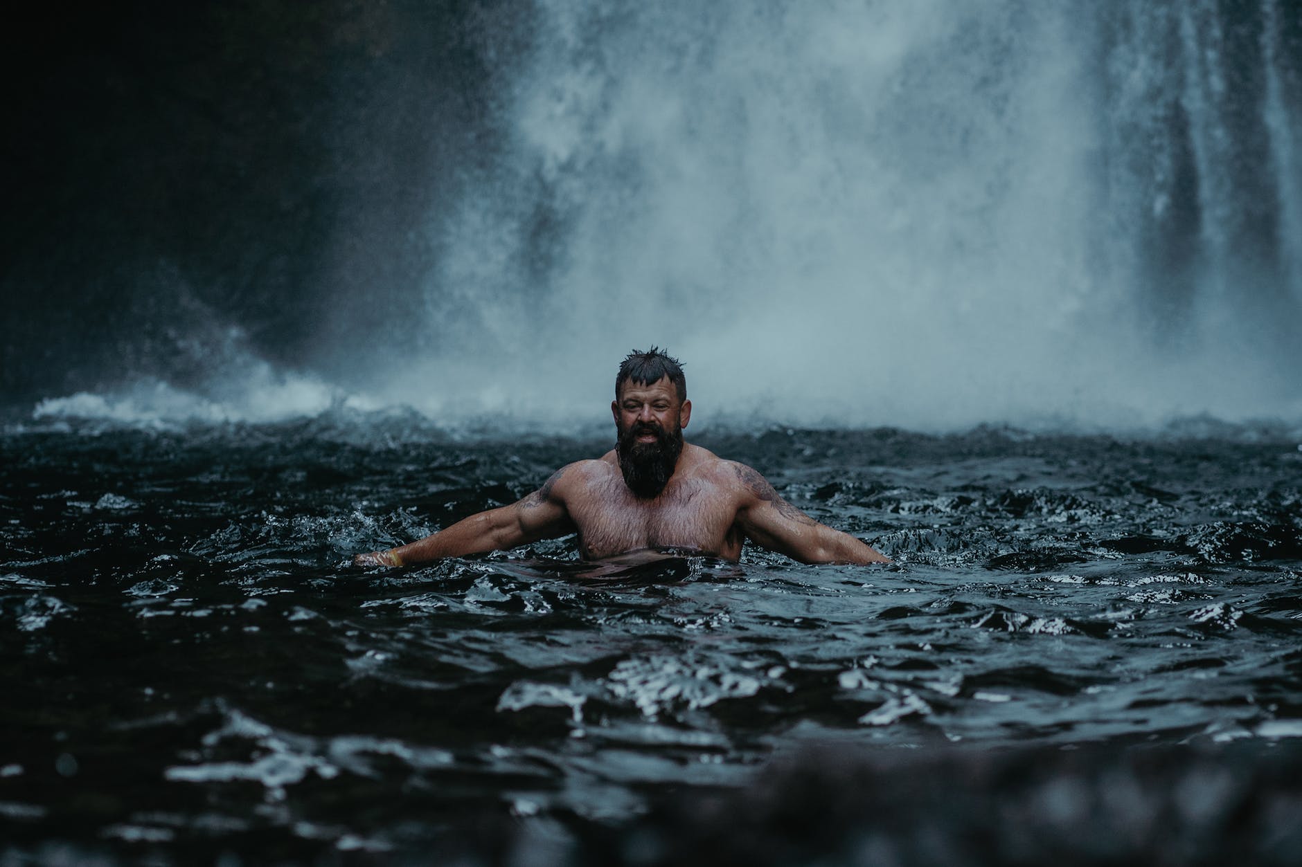 man during refreshing bath in waterfall in goa